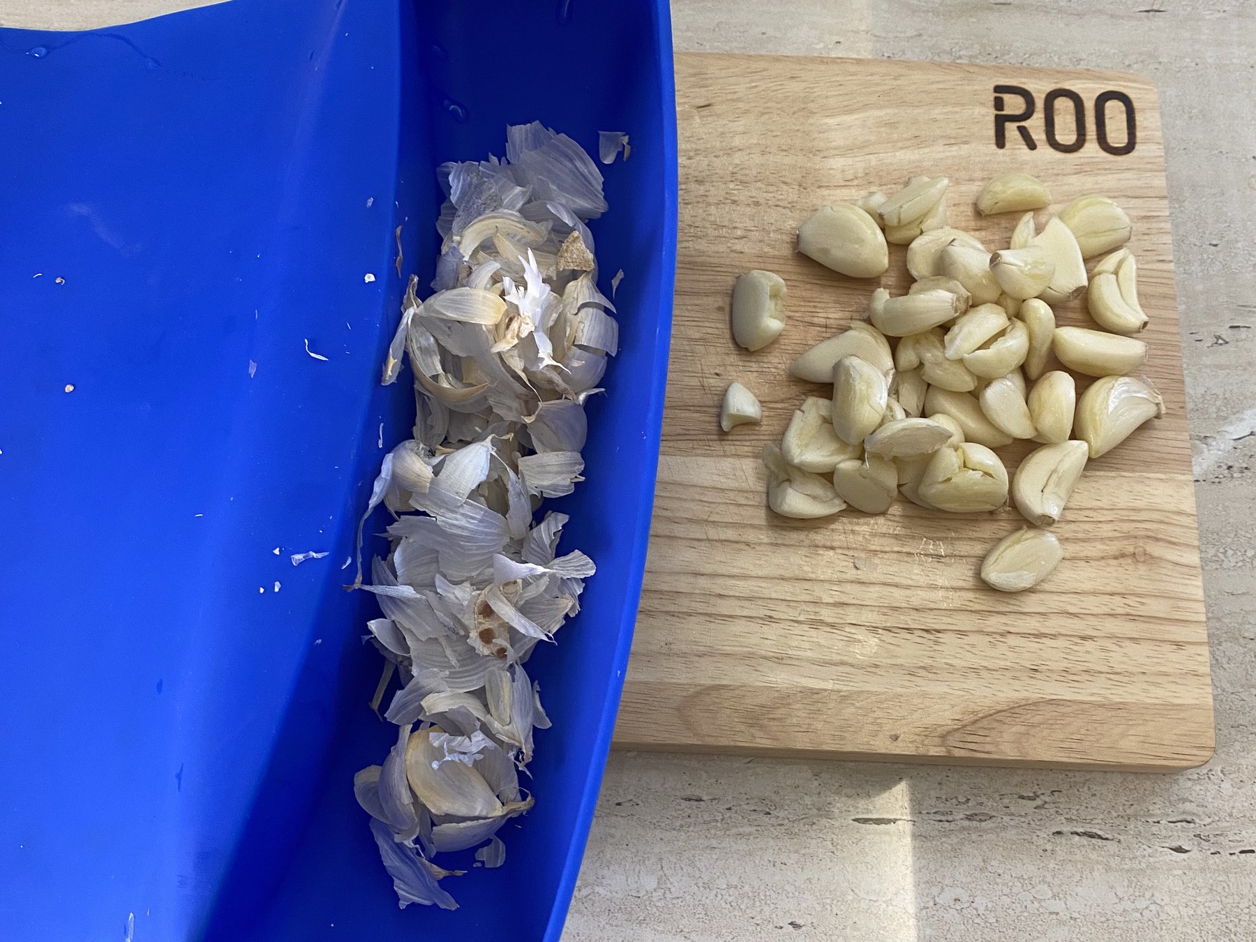 The same garlic, with the skins swept into the blue ROO pouch and the board clear